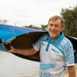 A man holds up a canoe on his shoulder