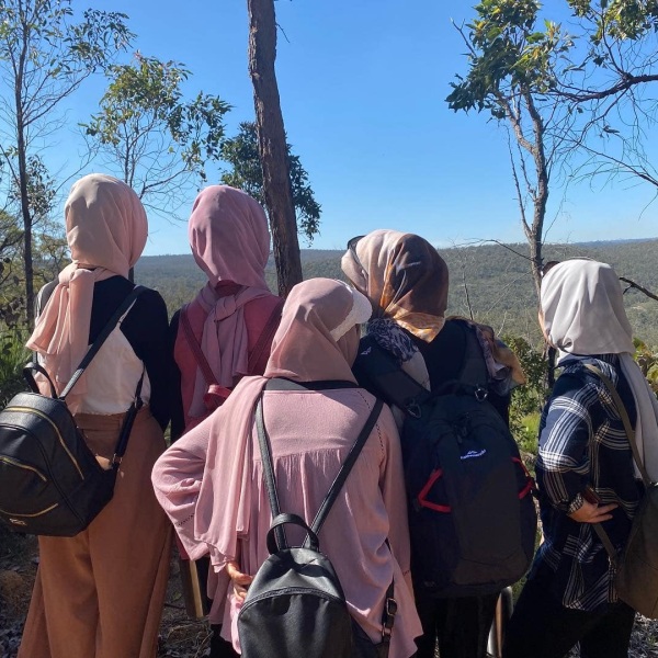 Group of women in headdresses in the forest staring at scenic environment