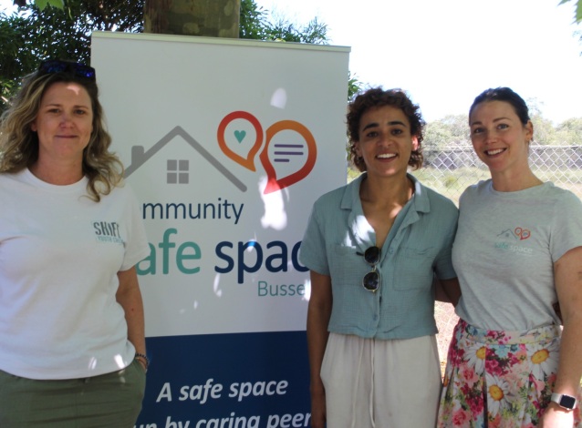 Three female volunteers standing in front of the banner for the busselton community safe space