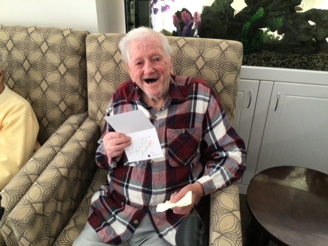 An aged care home resident holding up a card with joy