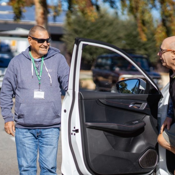A volunteer helping a client out of their car