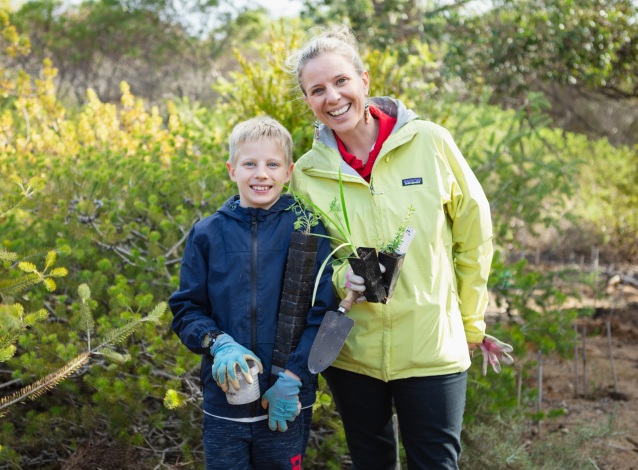A mother and son with gardening supplies, volunteering for a planting day