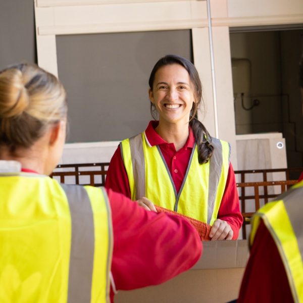 A group of volunteers wearing high-vis vests stand around a table