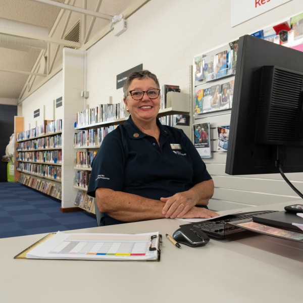 A woman sits behind a desk with a computer
