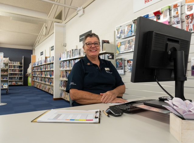 A woman sits behind a desk with a computer