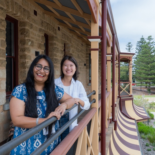 Two women stand on a balcony together