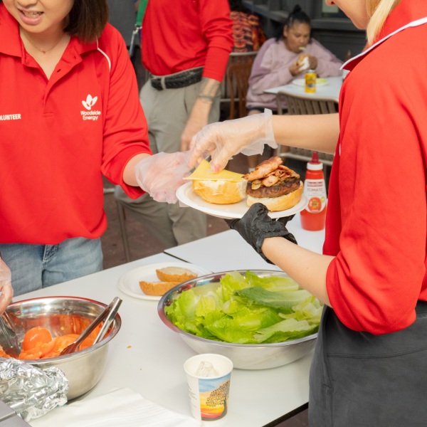 A group of corporate volunteers preparing a burger lunch