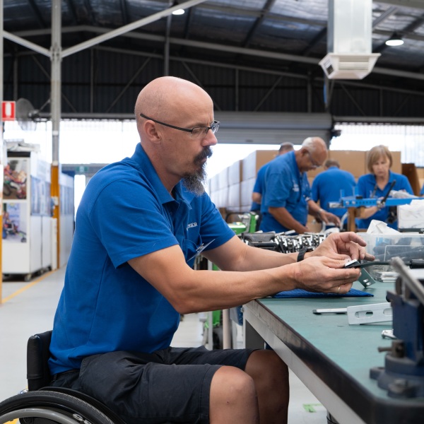A volunteer from Wheelchairs for Kids assembling parts in a factory